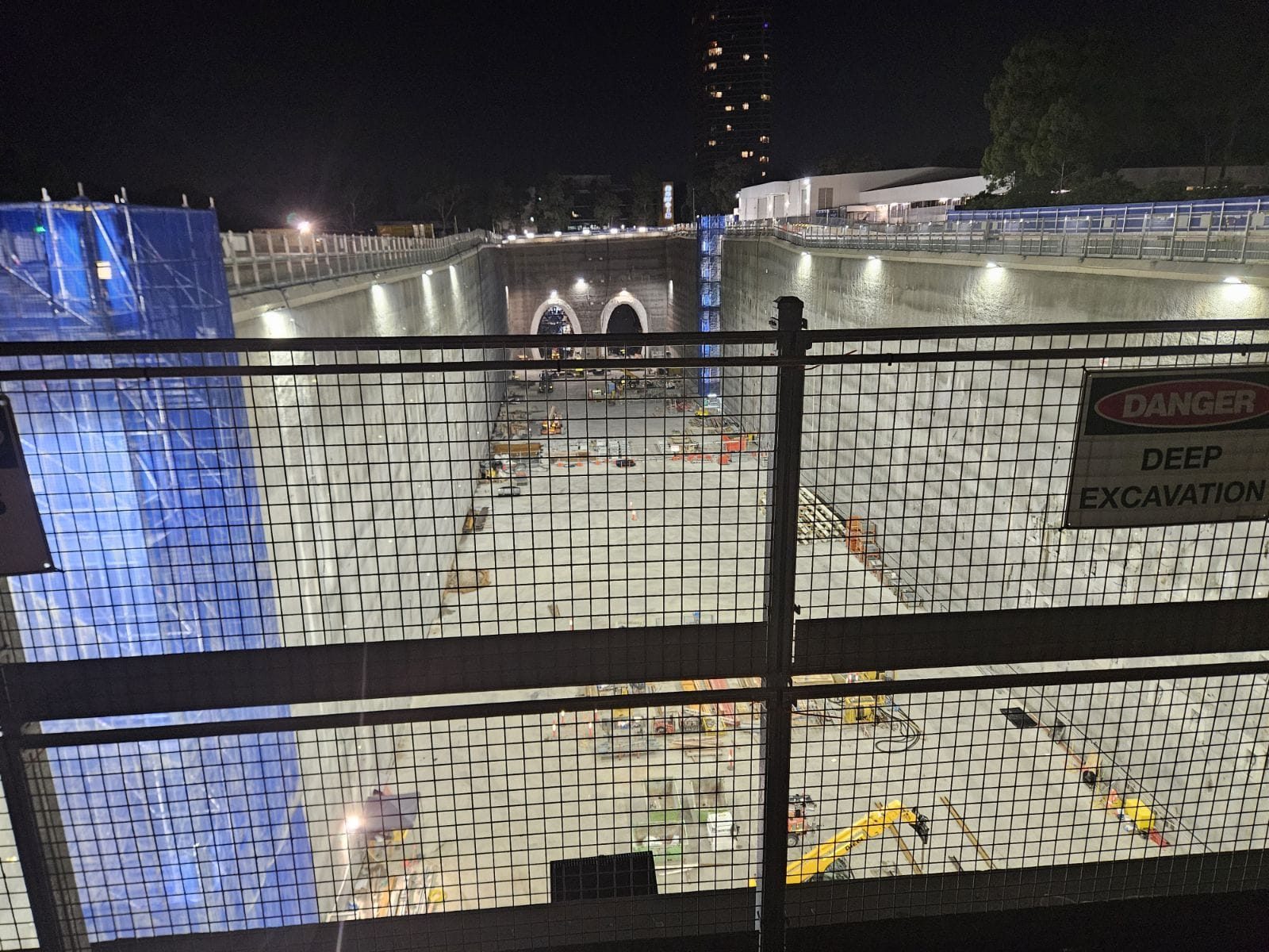Night shot of the floodlit station box — Giidjaa's wall-mounted LED floodlights lighting the deep excavation, twin tunne